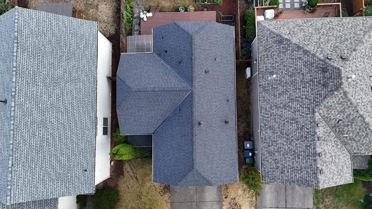 Aerial view of a new asphalt shingle roof on a Renton, WA home, between two older neighboring roofs